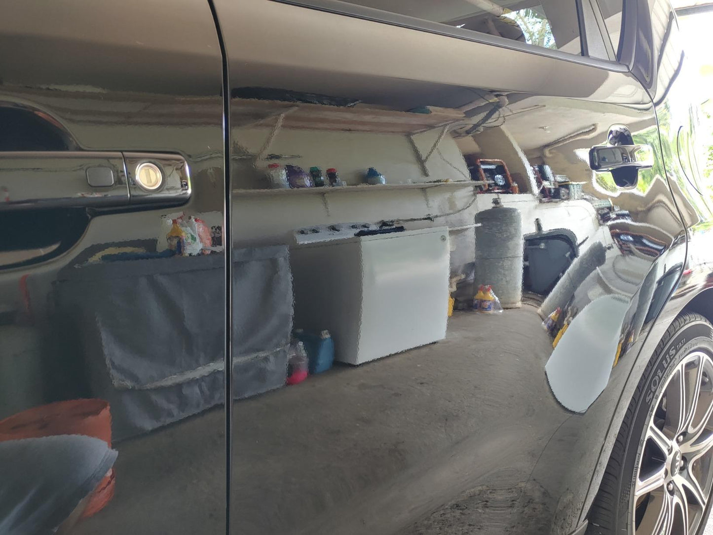 The client's garage reflecting off the glossy paint of a Kia Soul after paint correction, demonstrating a smooth and shiny finish.