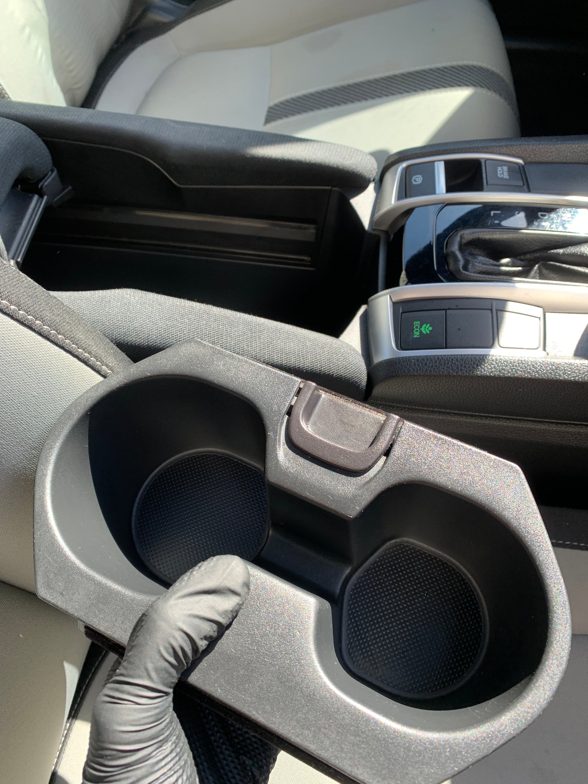 Close-up shot of a detailer holding a clean cup holder area, highlighting attention to detail in the cleaning process.
