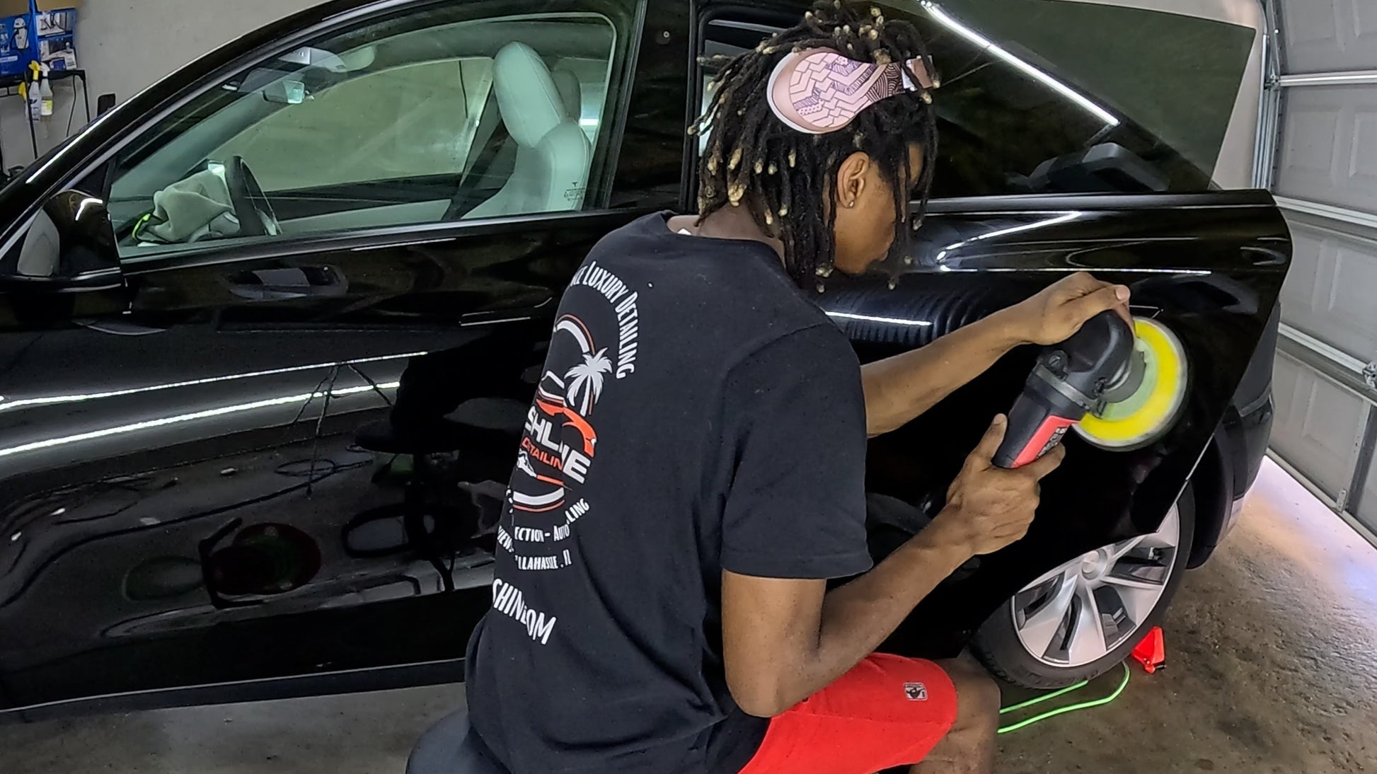 Applying wax to the Tesla’s exterior using a machine, creating a smooth, high-gloss finish for added protection