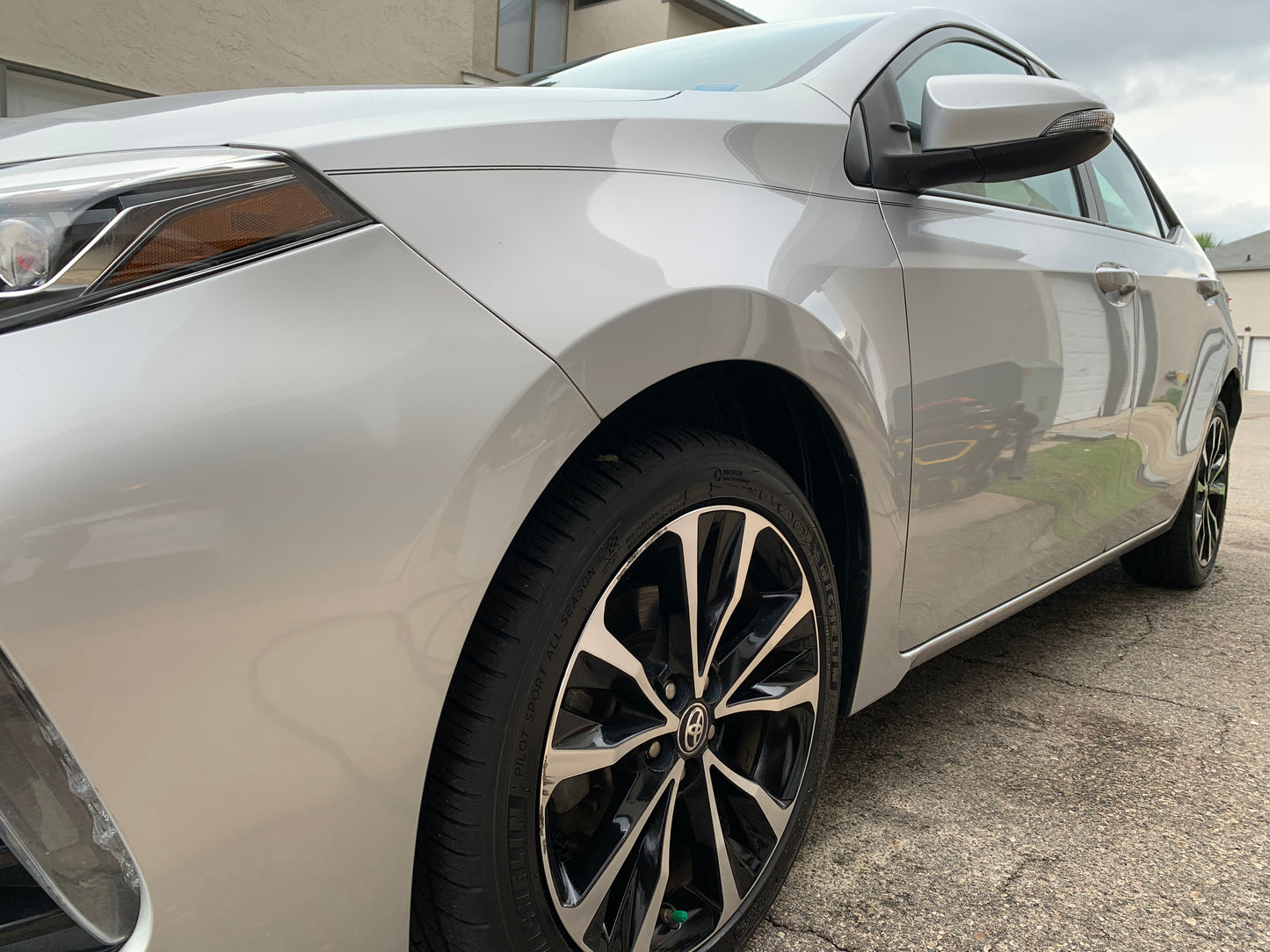 Low-angle shot from the front wheel, showcasing the entire side of a gleaming vehicle after professional detailing