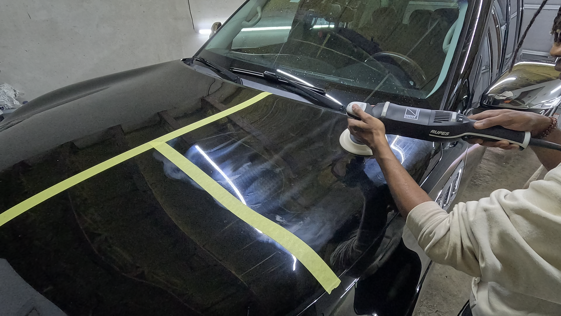 Technician using a Rupes rotary polisher to remove heavy defects, swirl marks, and scratches on a vehicle’s paint, restoring a smooth, glossy finish.